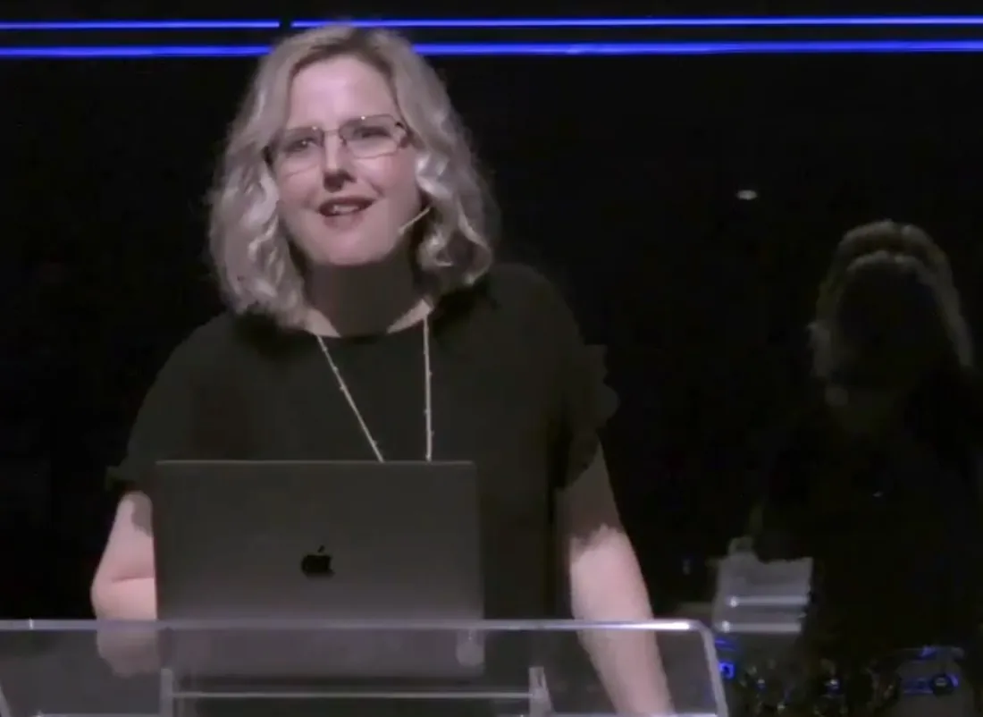 Kim Gilson at a glass lectern